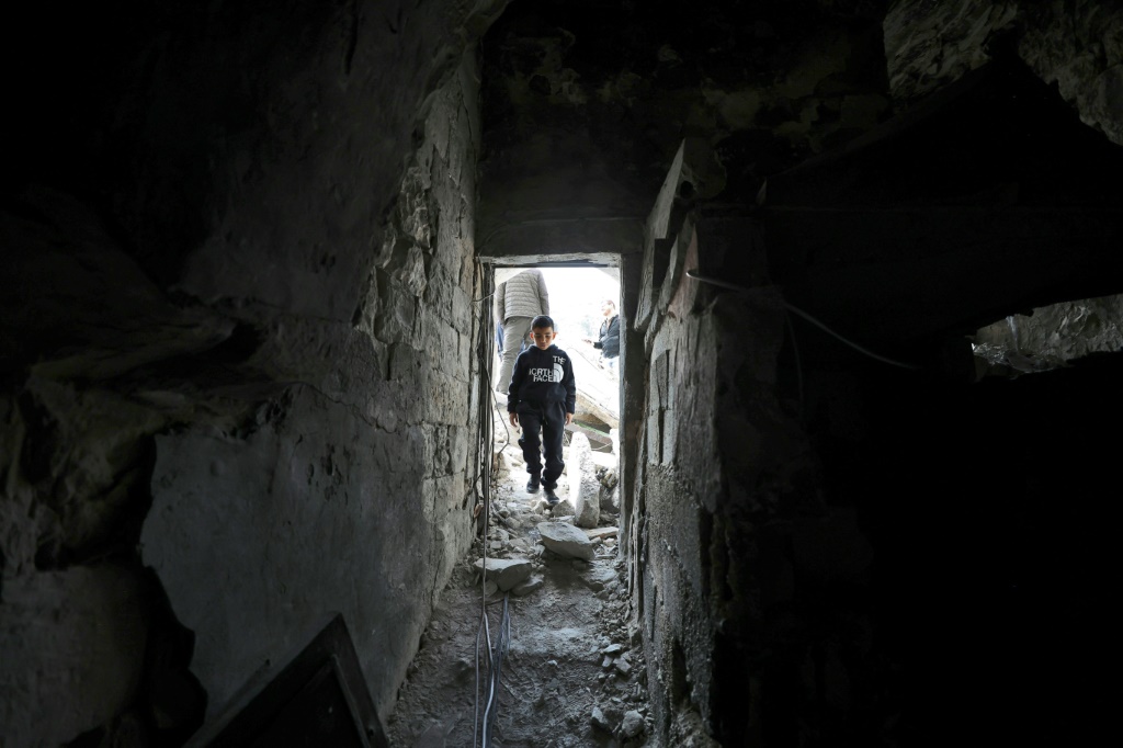 صبي يسير داخل منزل مهدم جزئيًا في البلدة القديمة بنابلس (ا ف ب)
